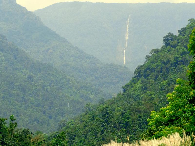 Waterfall seen across green hills from the river at Bisnakandi